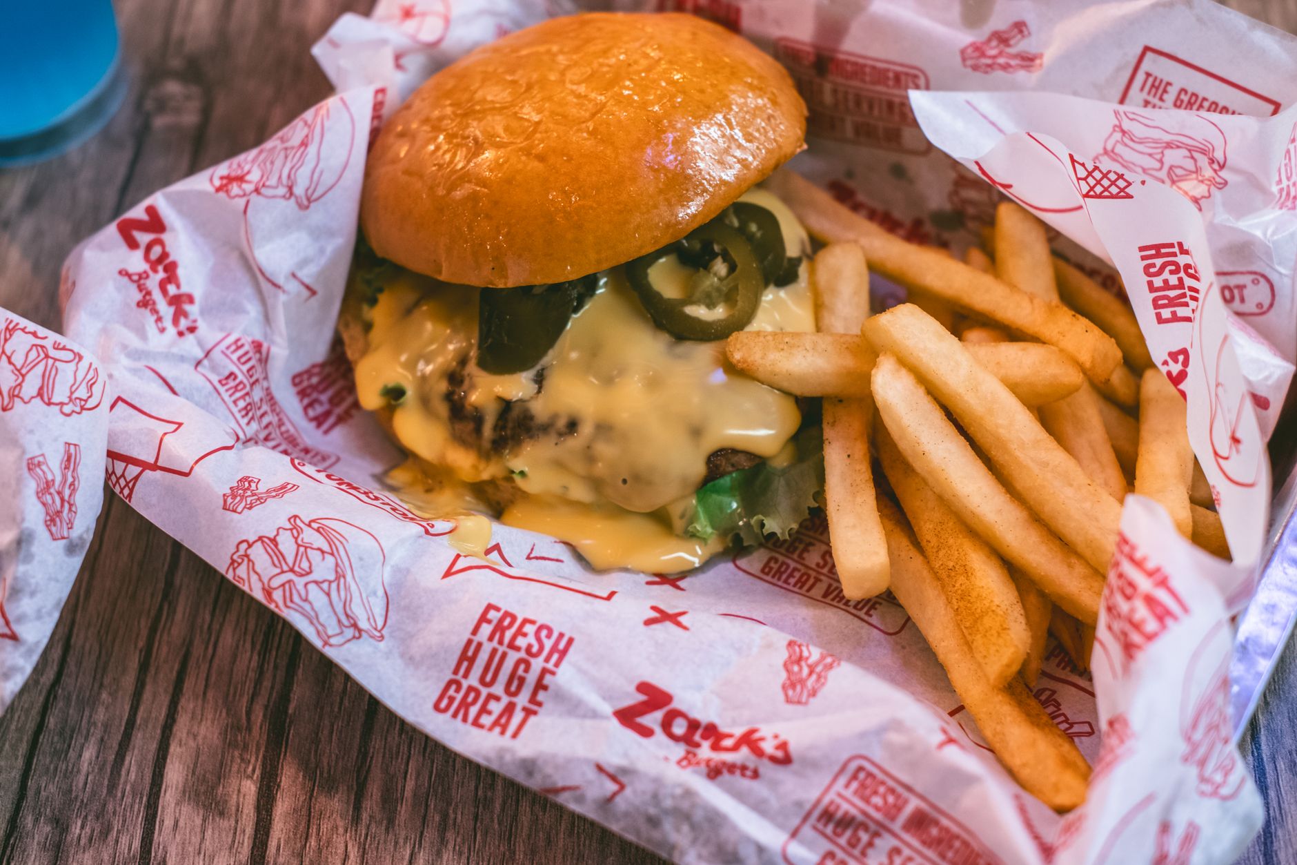 Mouth-watering cheeseburger with jalapenos and crispy fries in fast food restaurant.