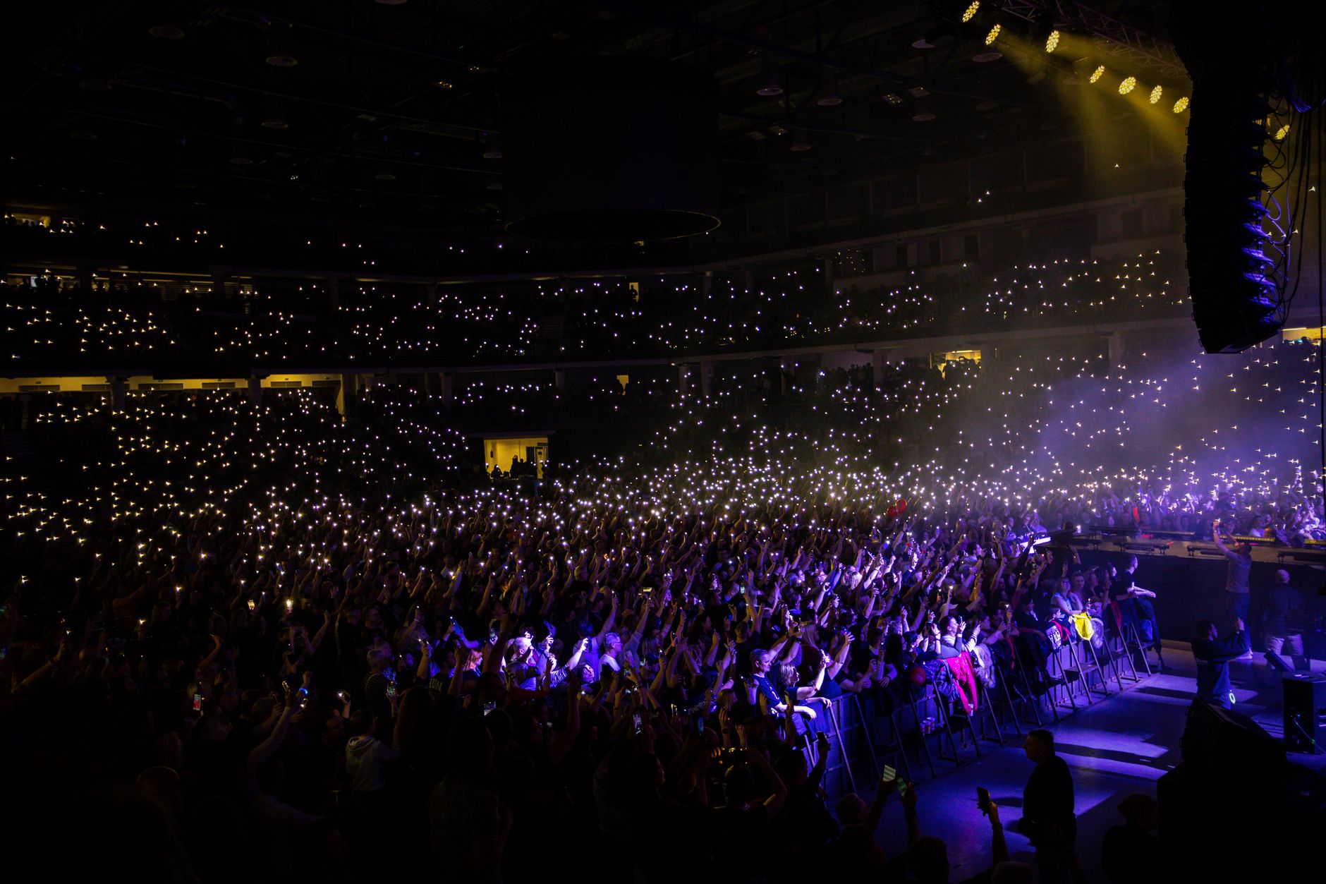 A packed indoor concert with audience lights creating a stunning visual display.