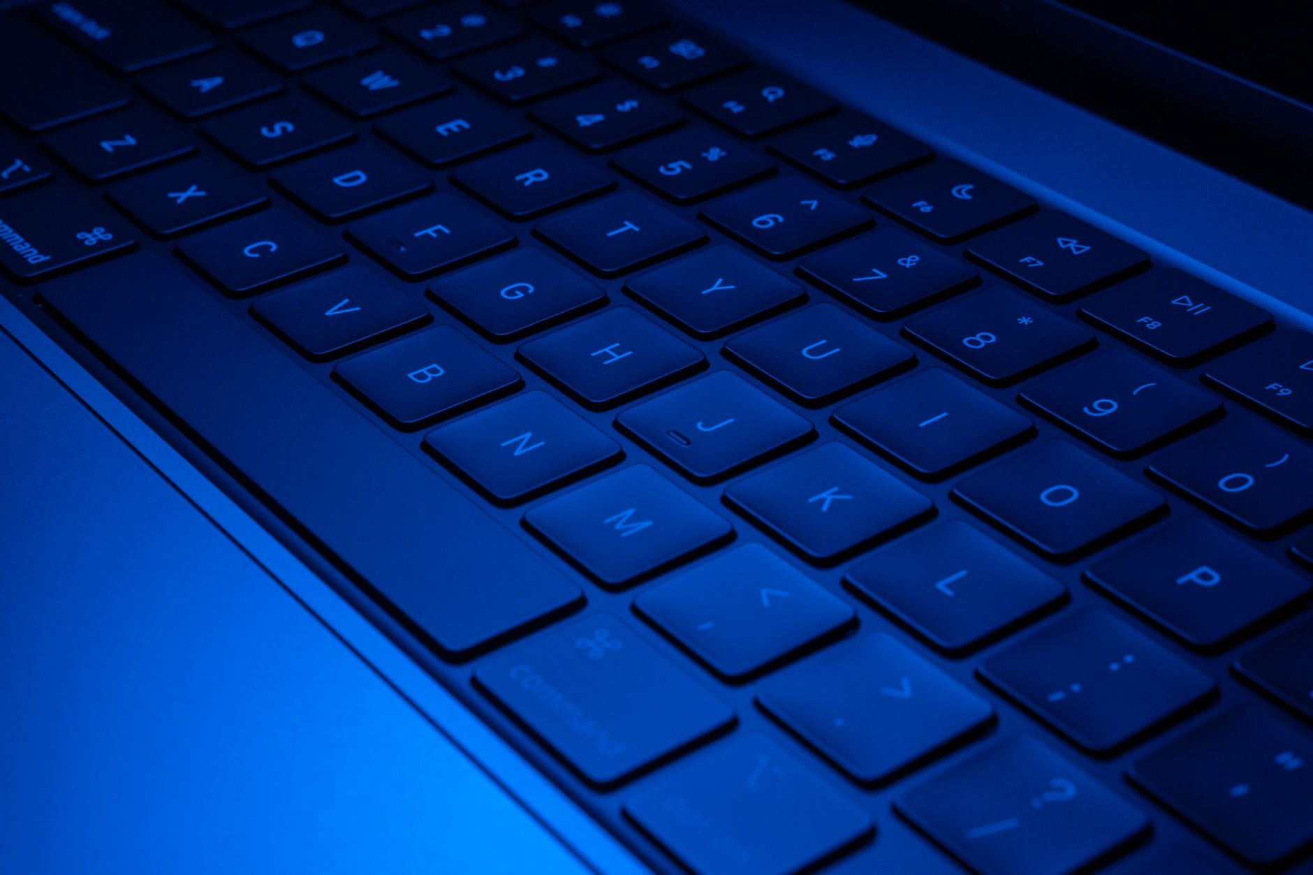 Close-up image of a laptop keyboard illuminated with blue light, showcasing modern technology design.