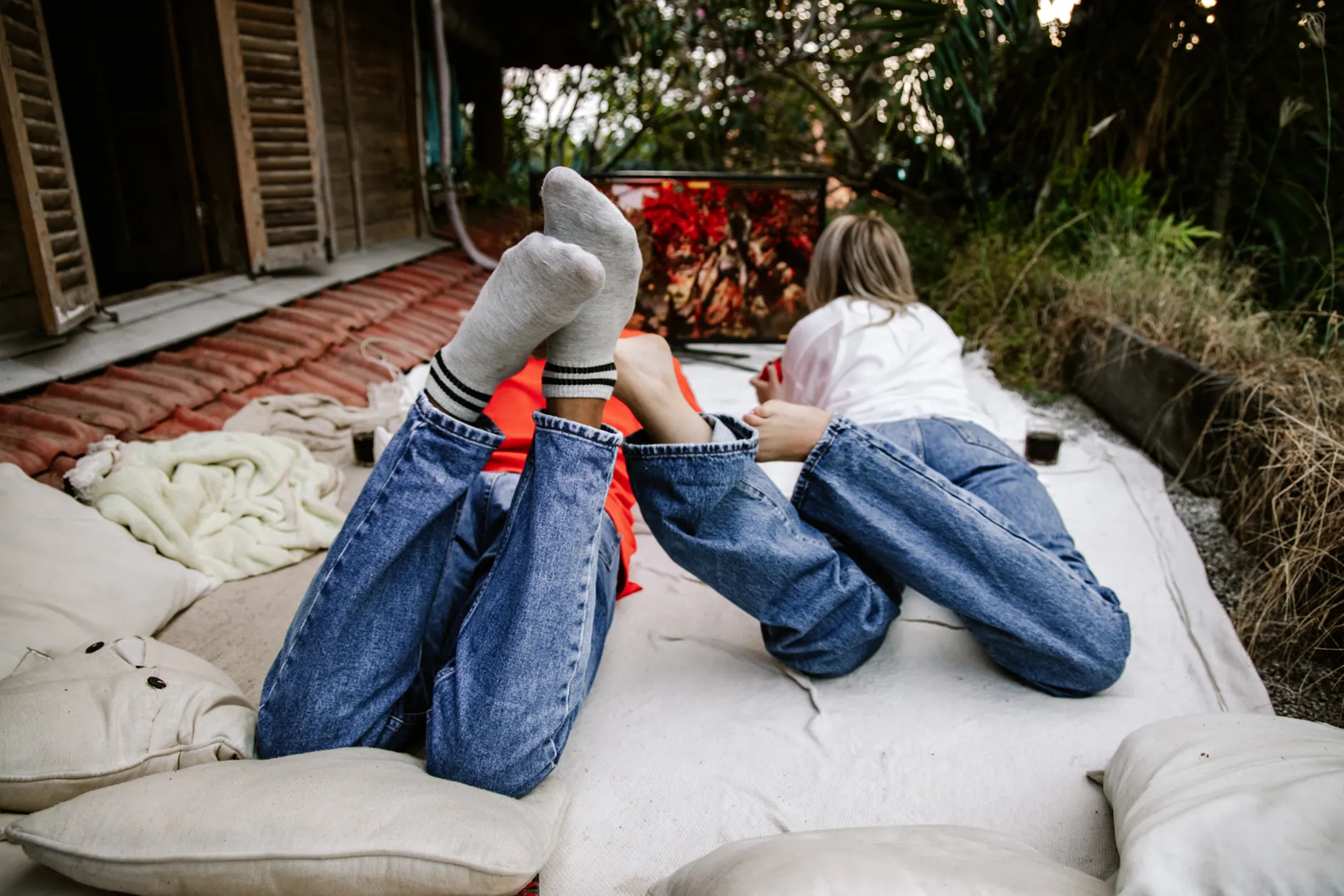 Two adults enjoying an outdoor movie night in a cozy setup, surrounded by nature.