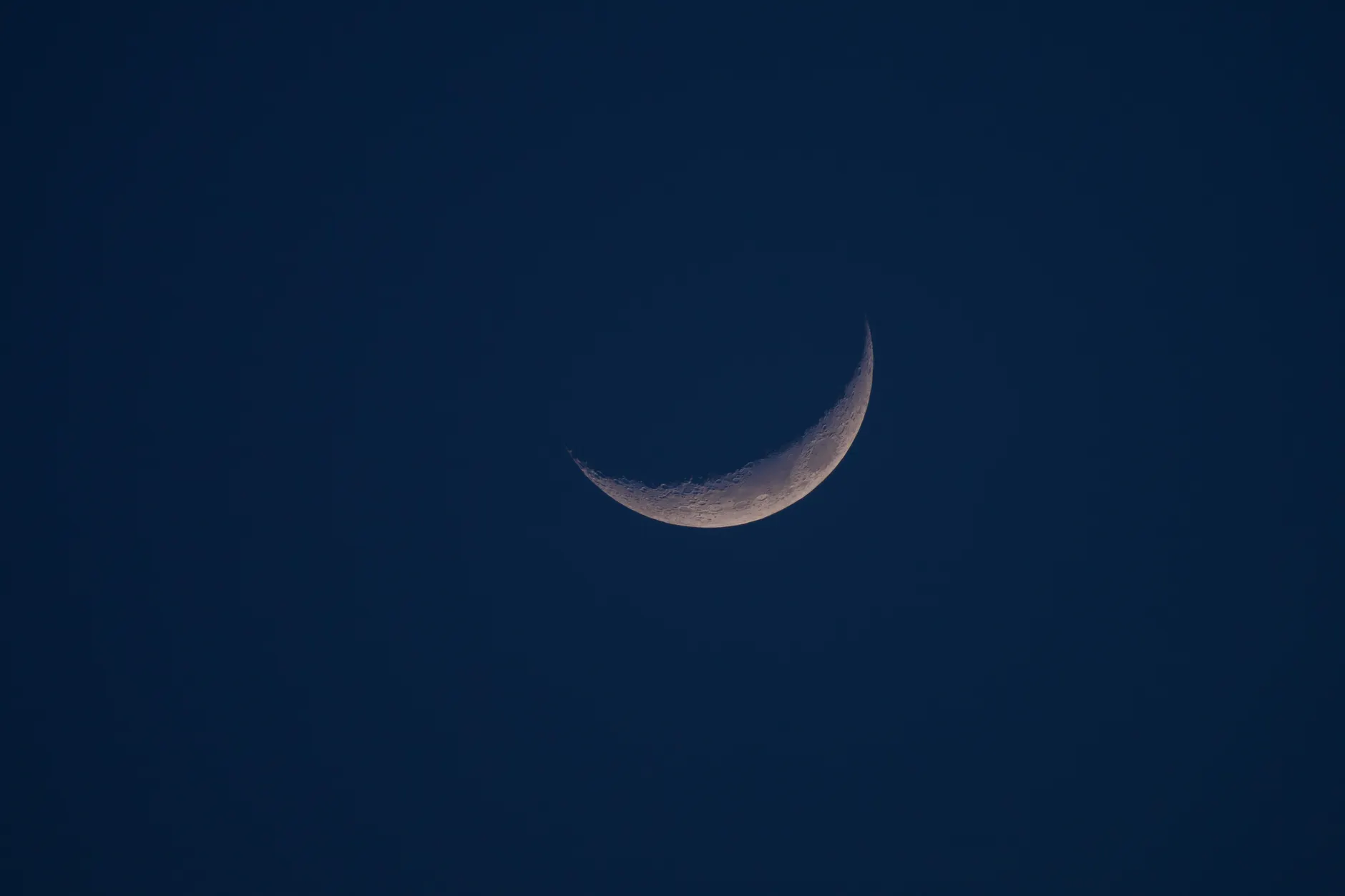 A close-up of a crescent moon against a dark night sky, highlighting lunar details.
