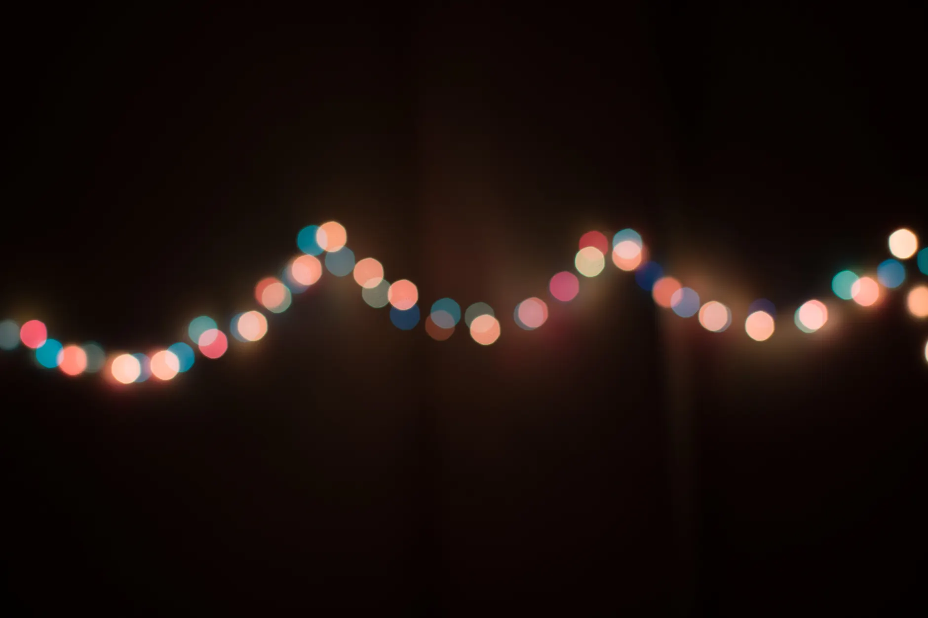 Defocused string lights creating a colorful bokeh effect on a dark background, evoking a festive mood.