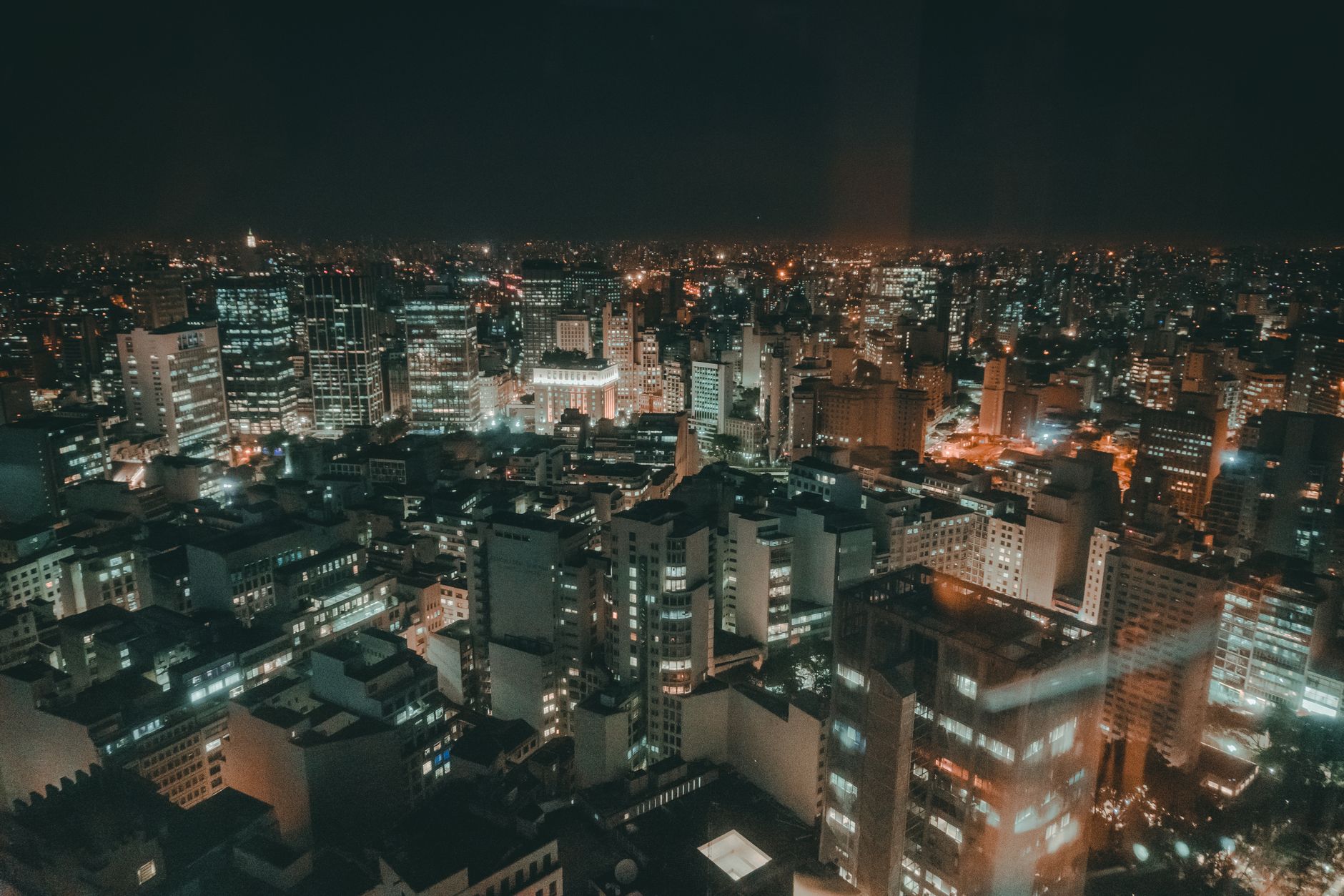 Stunning aerial view of a cityscape at night, showcasing vibrant lights and modern skyscrapers.